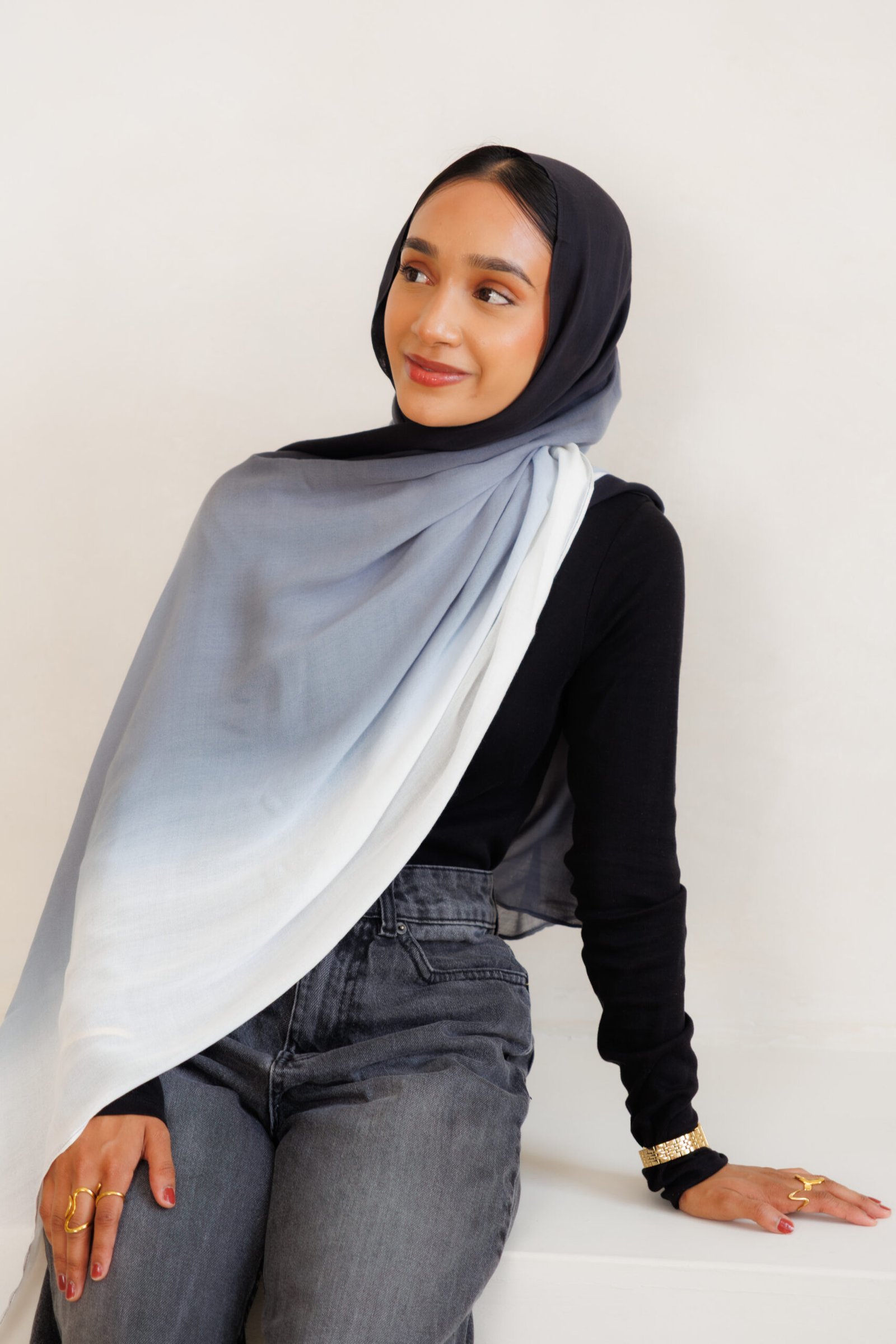 Woman wearing a black and grey gradient hijab with a long flowing drape across the front
