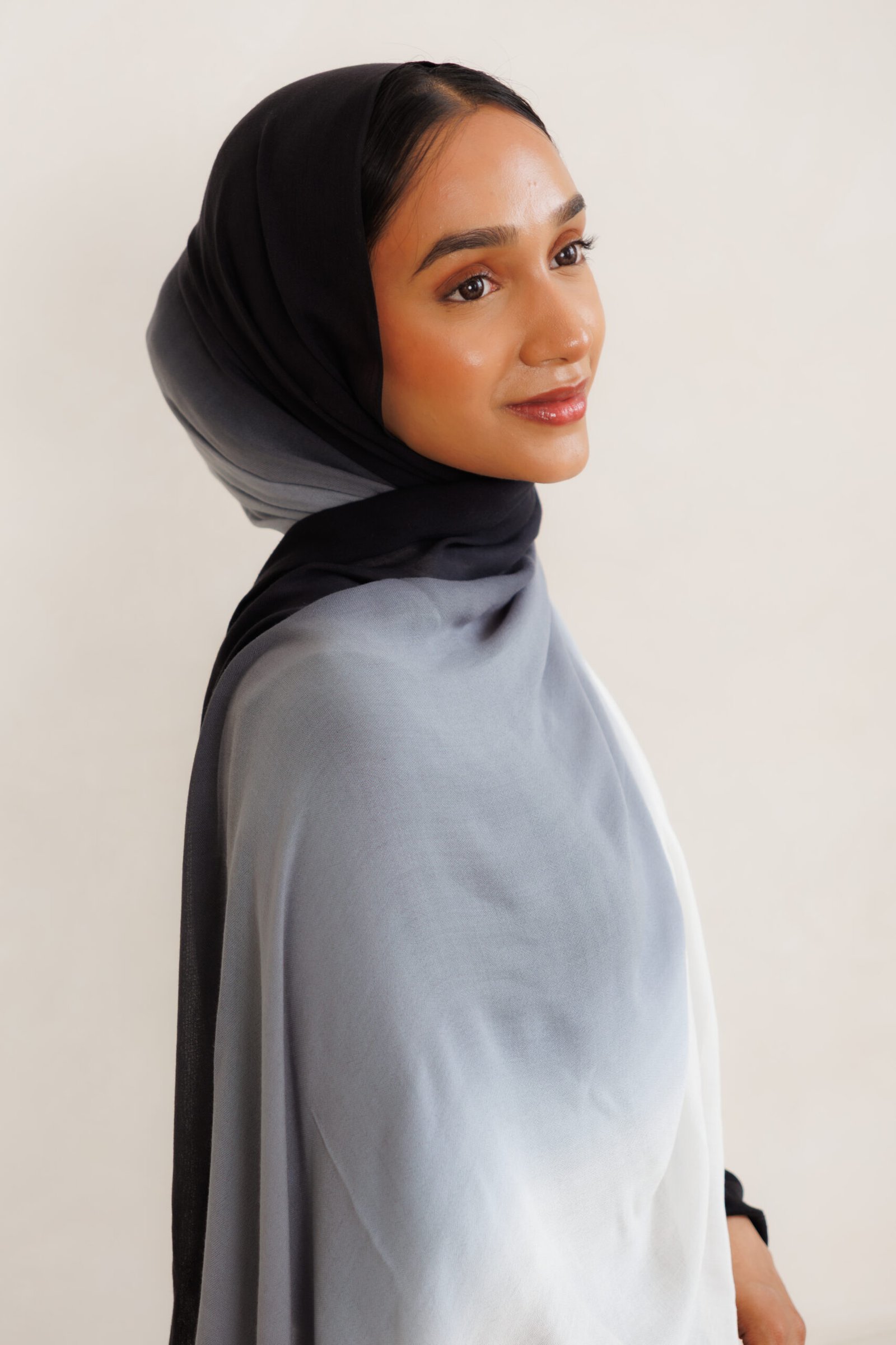 Side view of a woman wearing a black and grey gradient hijab with layered draping