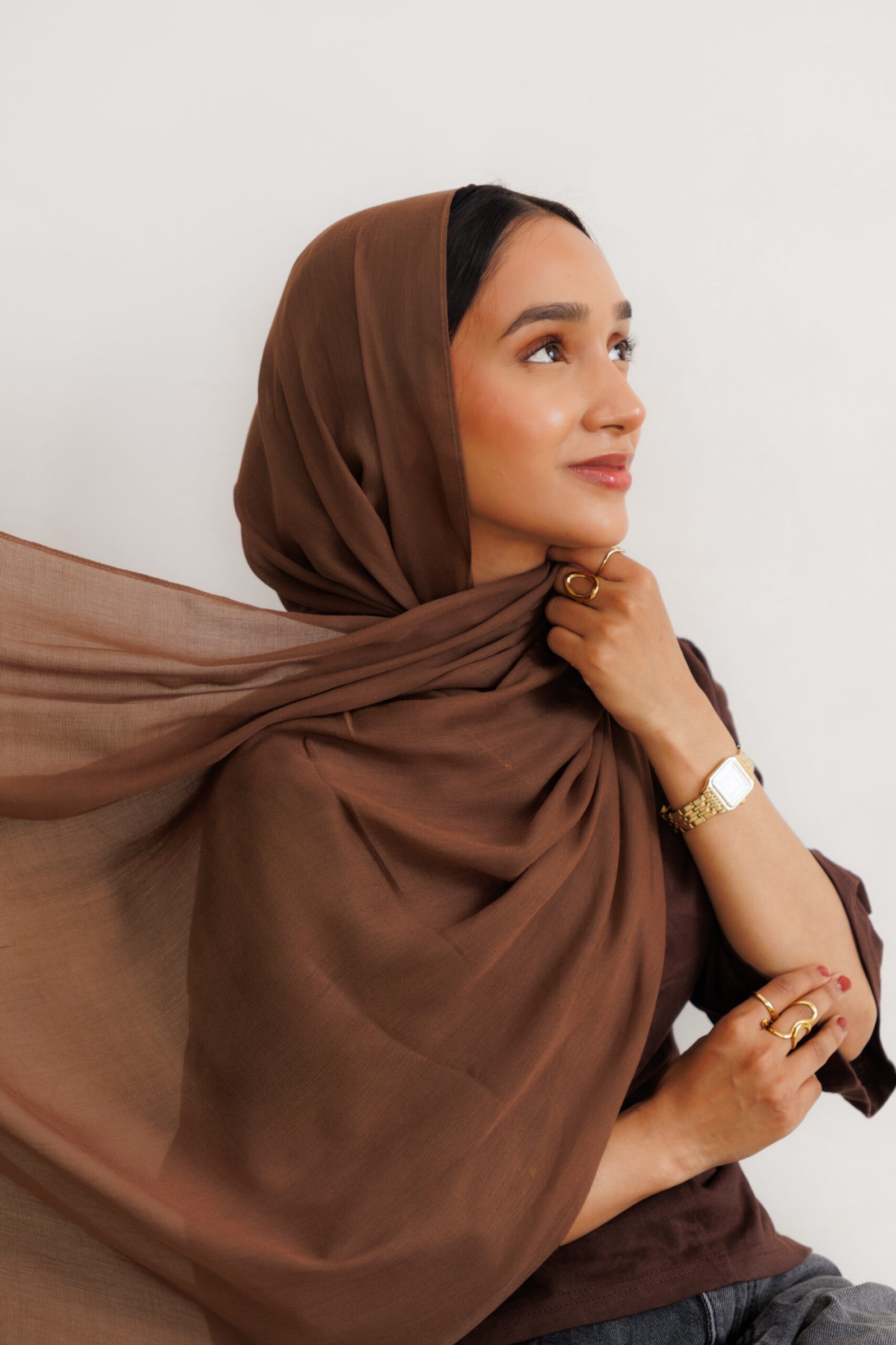 Woman wearing a dark brown hijab with a long flowing drape extending from the neck