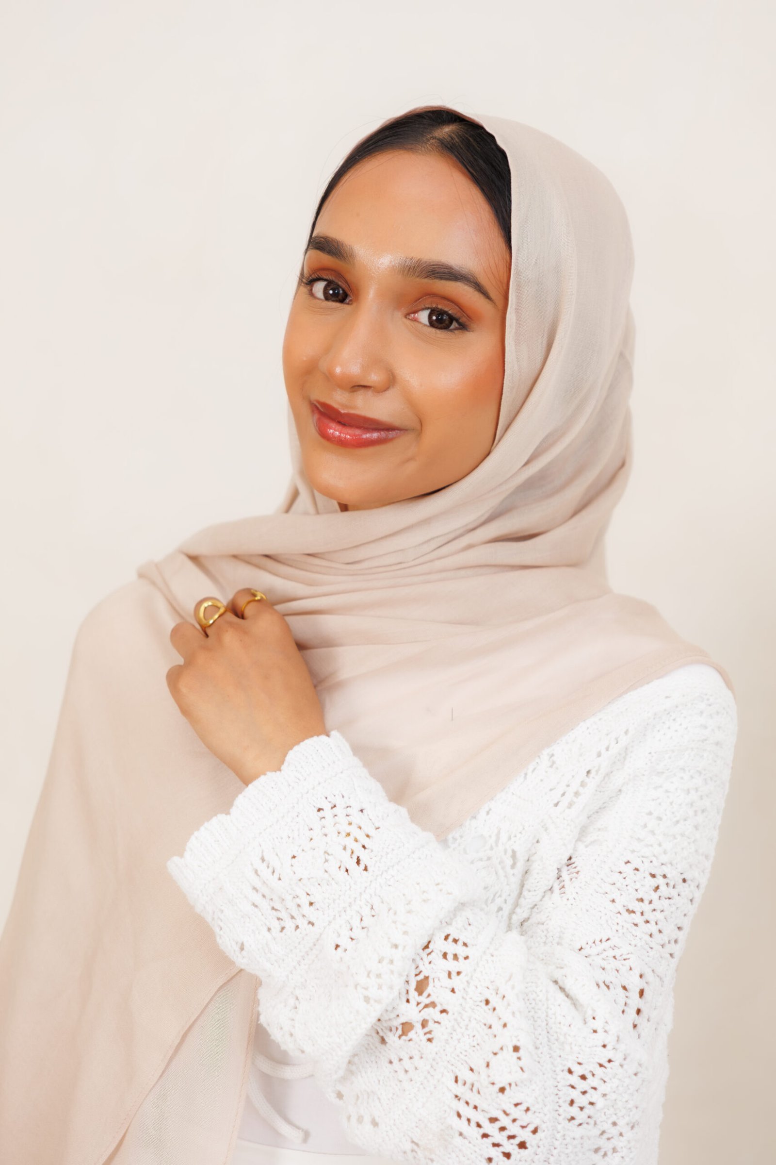 Woman wearing a nude beige hijab with layered folds around the face and neck