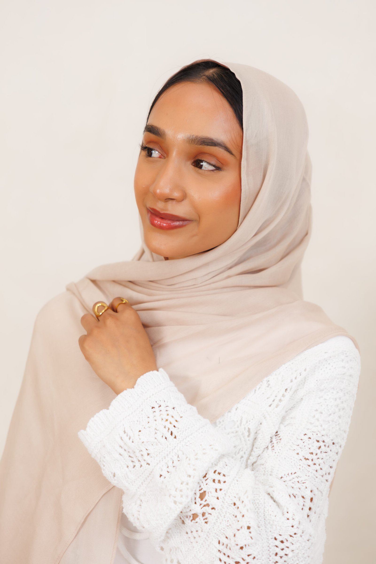 Woman wearing a nude beige hijab with softly layered draping around the head and shoulders